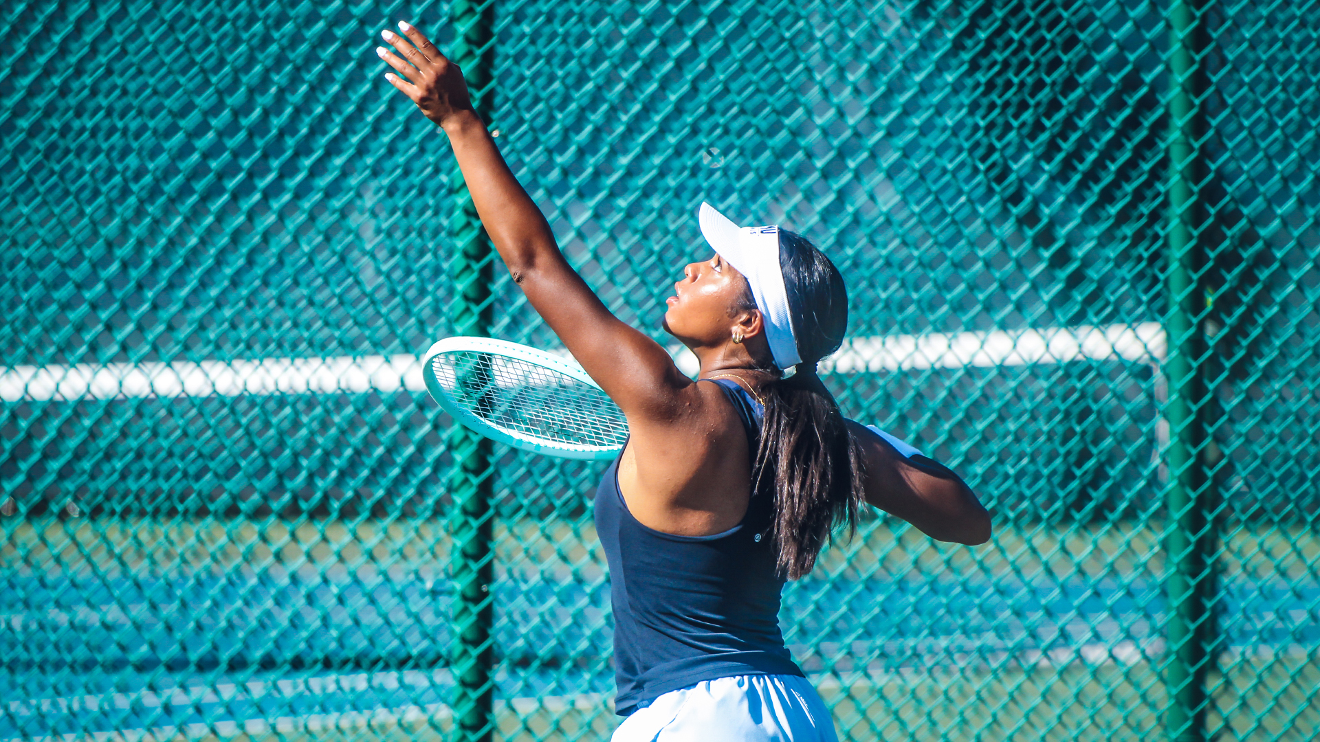 Alanna Reyes serving a tennis ball